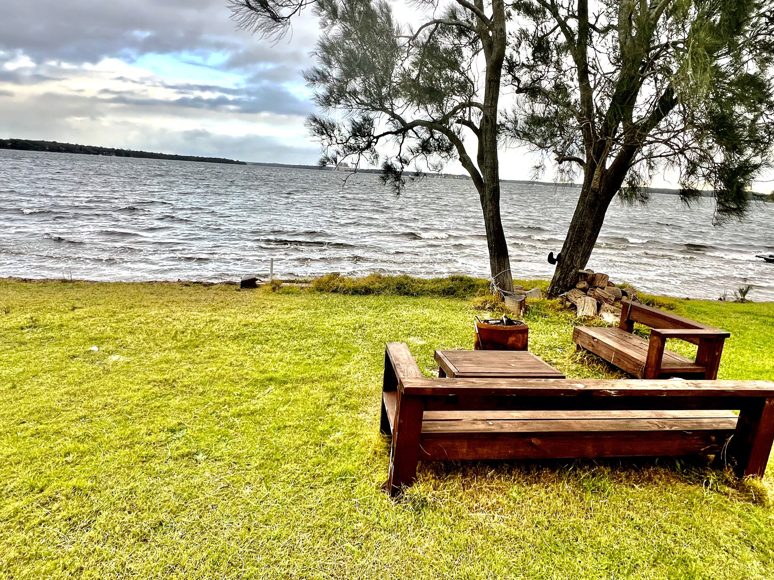 A dramatic shot of the outdoor sitting place besides the tree, a few steps away from the lakeside